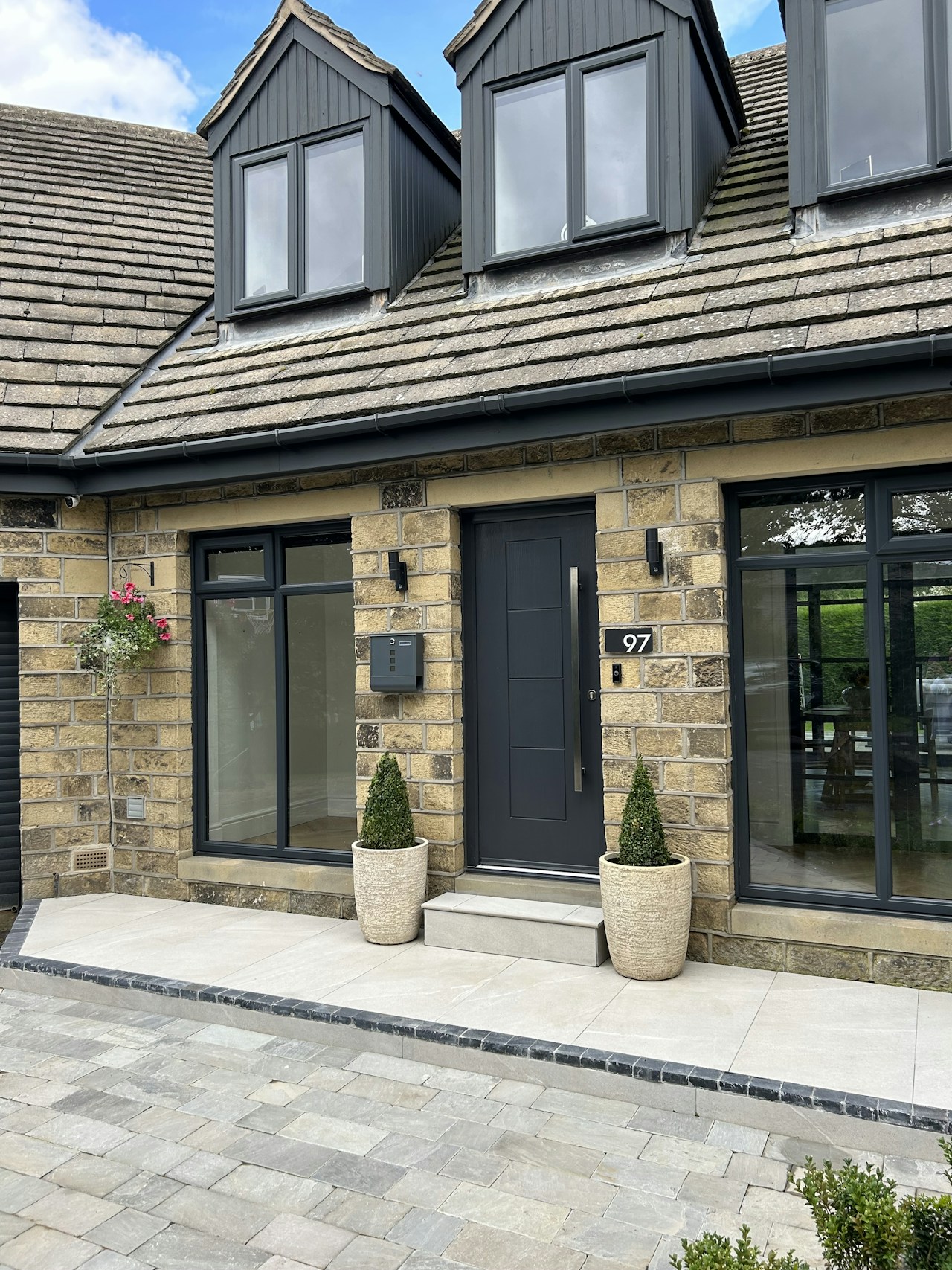 Stone house with a grey block-paved front drive