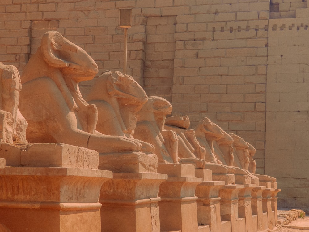 a row of statues in front of a brick wall