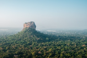a very tall mountain surrounded by lush green trees