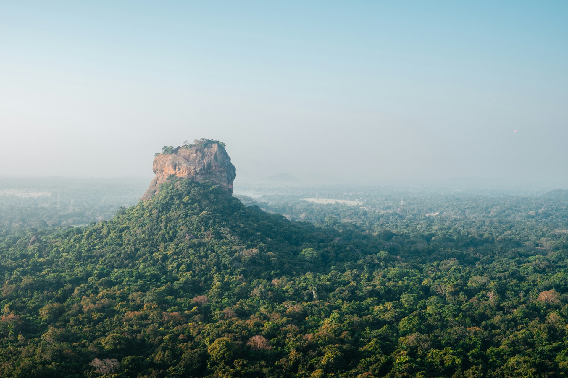 a very tall mountain surrounded by lush green trees