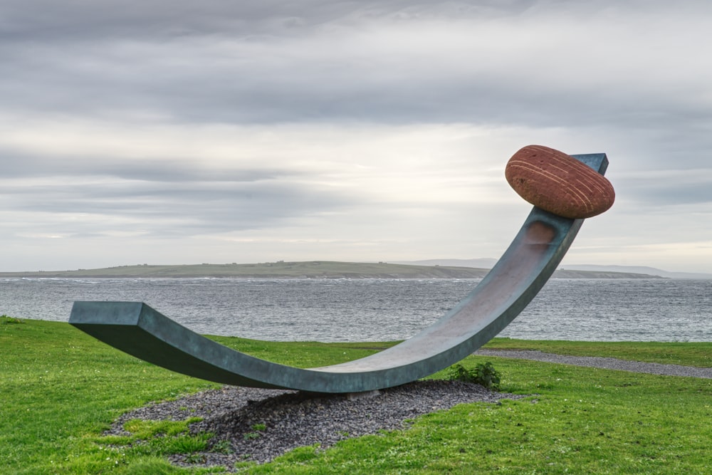 a sculpture in the grass near a body of water