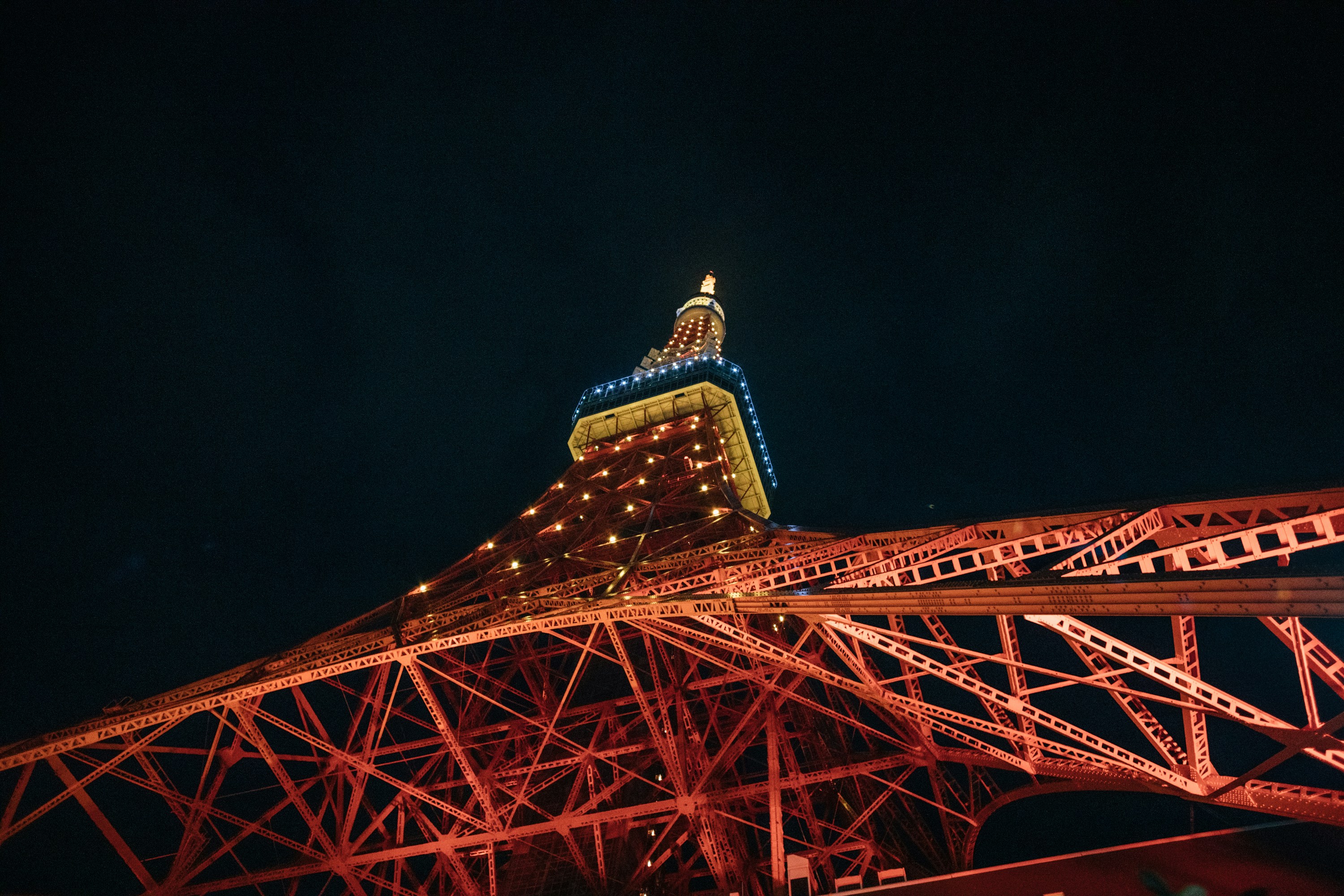 Eine rote Brücke mit einem hohen Turm, der nachts beleuchtet wird