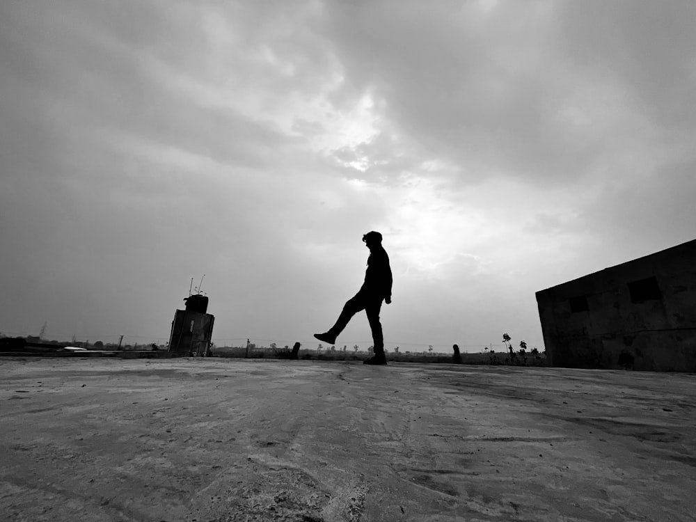 a man walking across a parking lot under a cloudy sky