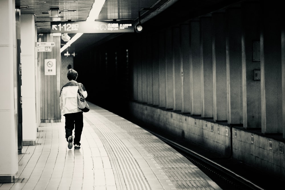 a person with a backpack walking down a subway platform