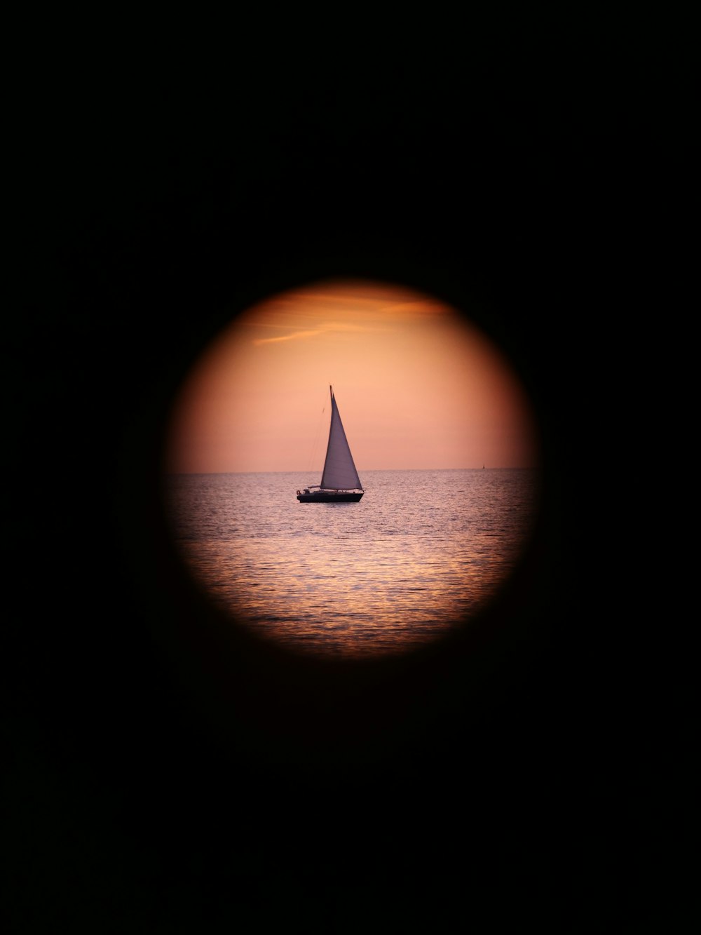 a sailboat is seen through a hole in the water