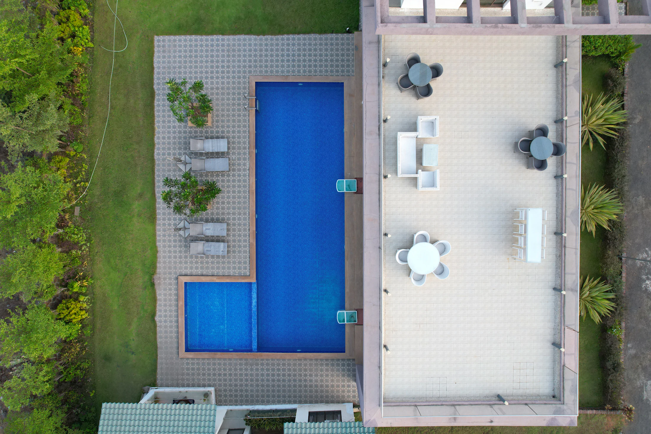 Aerial view of a pool and paved patio surrounded by planting