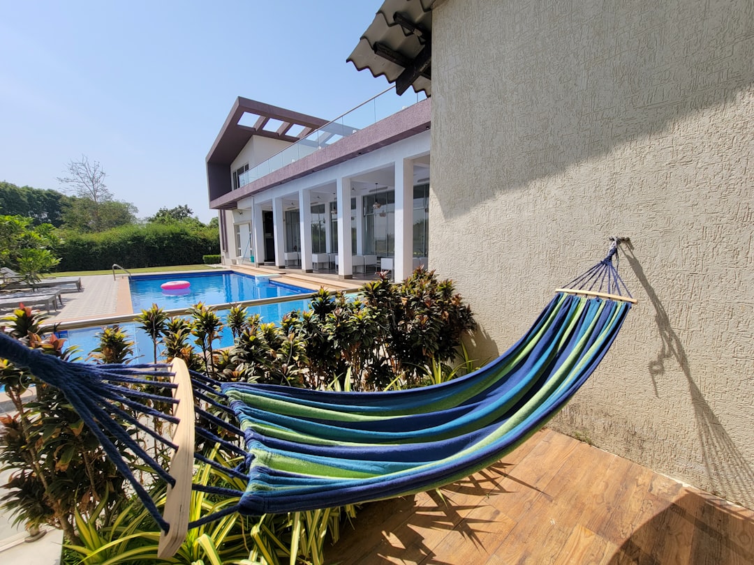 a blue hammock sitting in front of a house, Hammock on a balcony with a swimming pool view