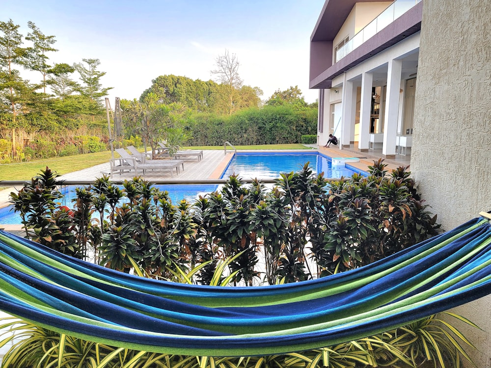 a blue and green hammock sitting next to a swimming pool