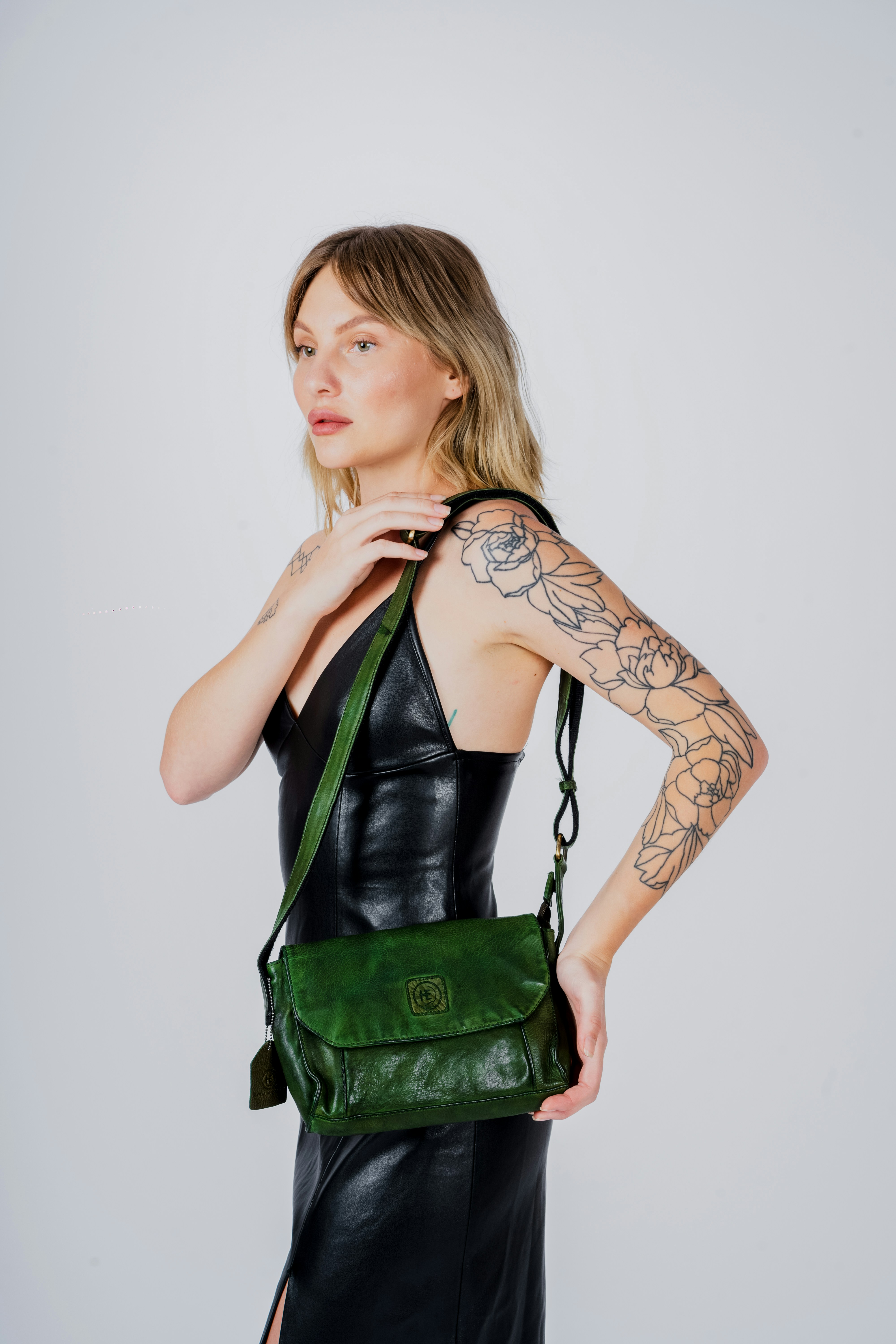 a woman in a black dress holding a green bag