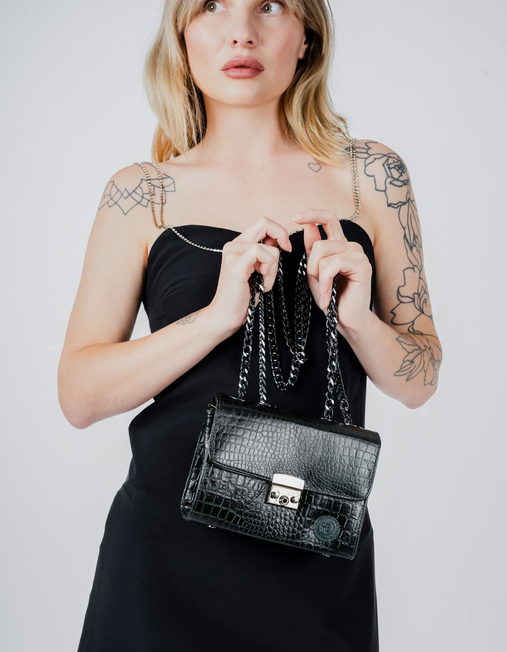 a woman in a black dress holding a black purse
