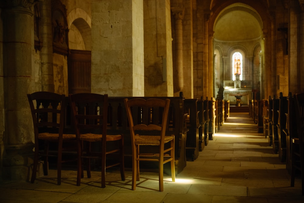 a row of wooden chairs sitting inside of a church