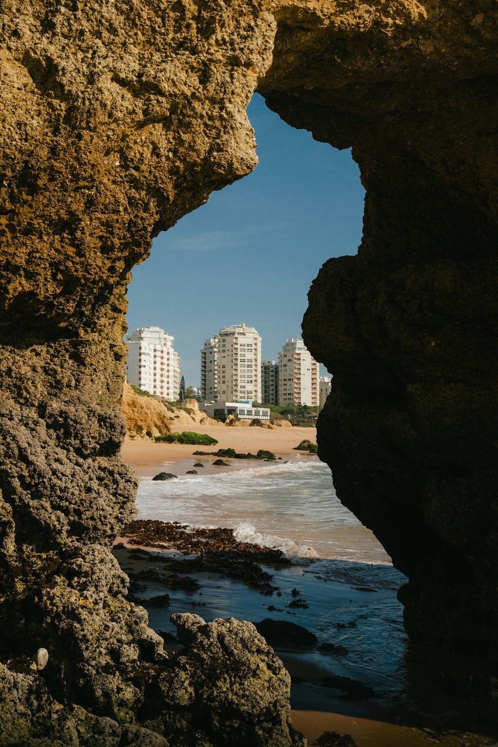 uma vista de uma praia através de um buraco em uma rocha
