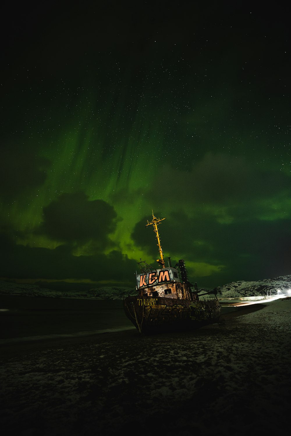 a boat sitting on top of a sandy beach under a green sky