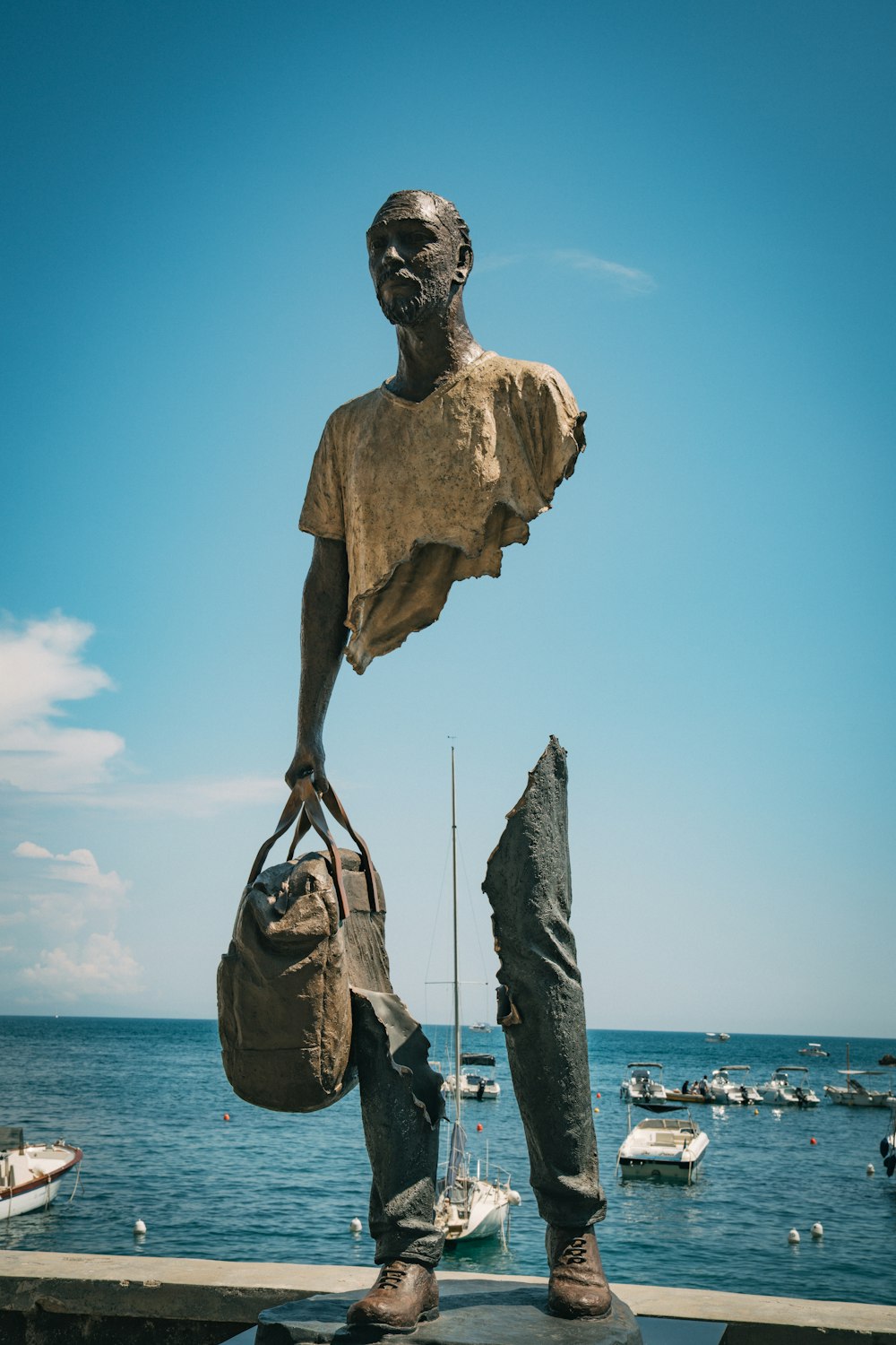 a statue of a man holding a bag near a body of water