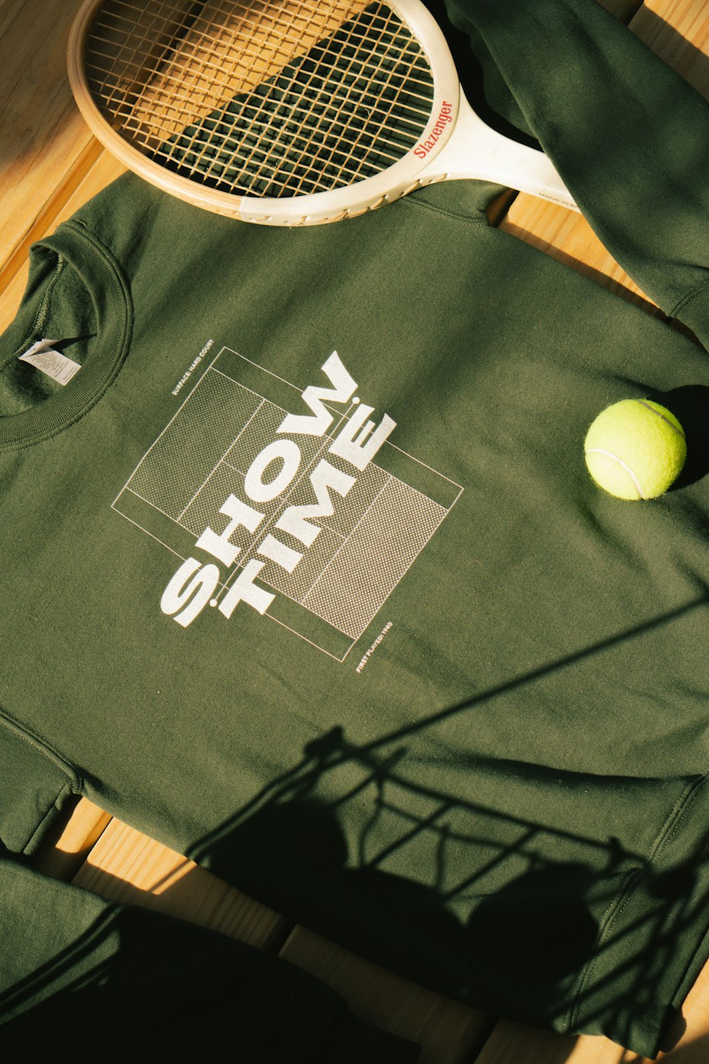 a tennis racket and a t - shirt on a wooden floor