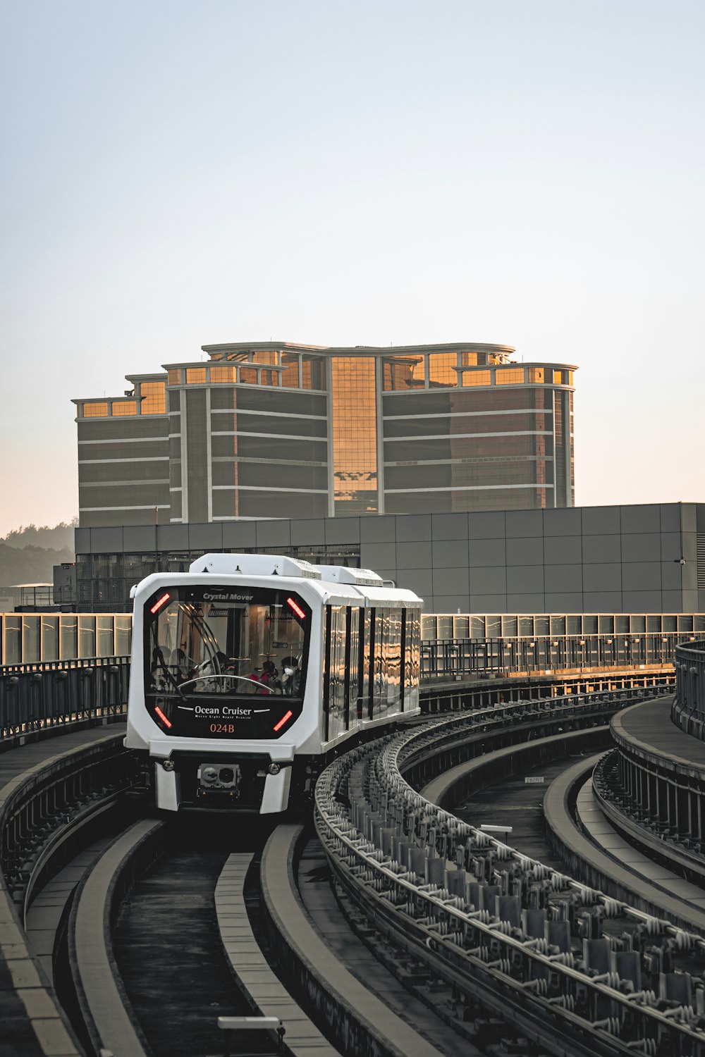 a white train traveling down train tracks next to a tall building