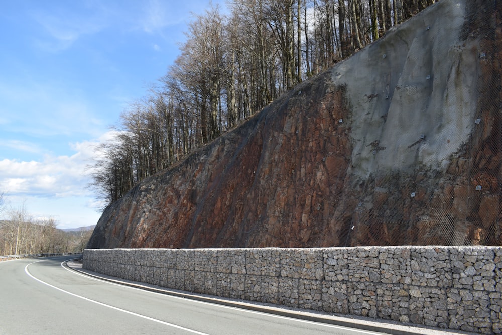 a curved road with a rock wall on the side