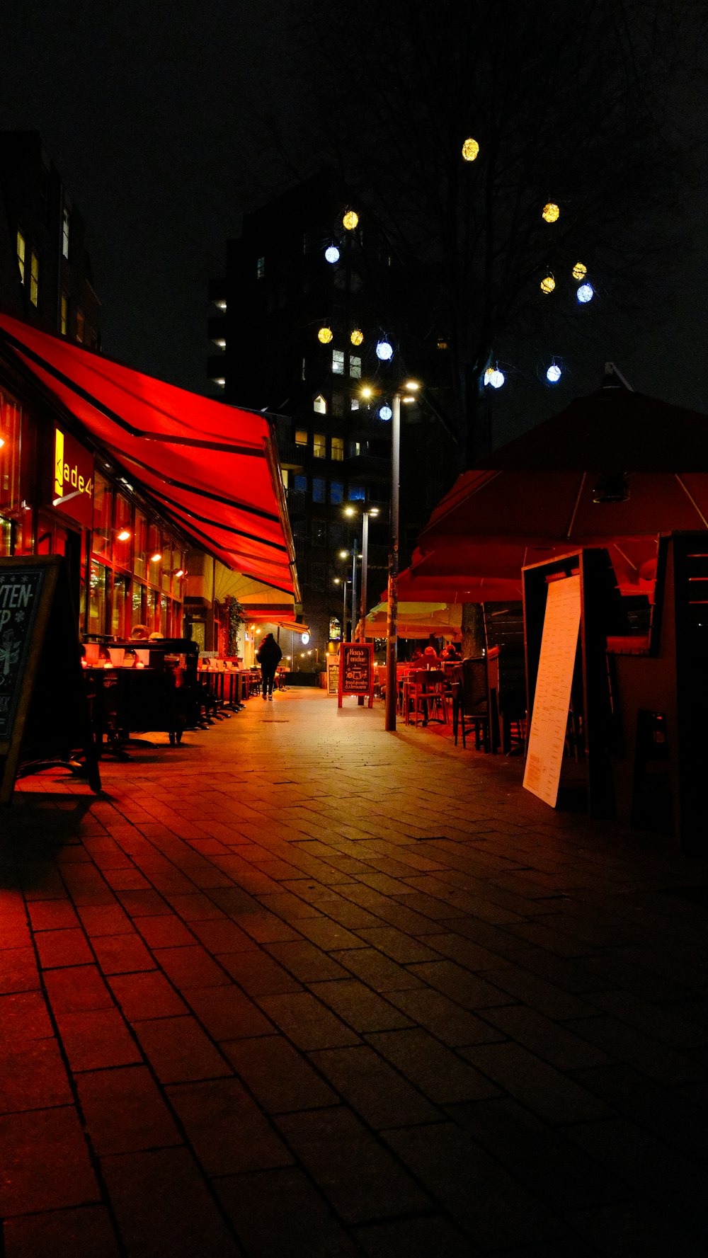 a city street at night with a red awning