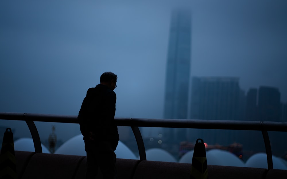 a man standing on top of a bridge next to a tall building
