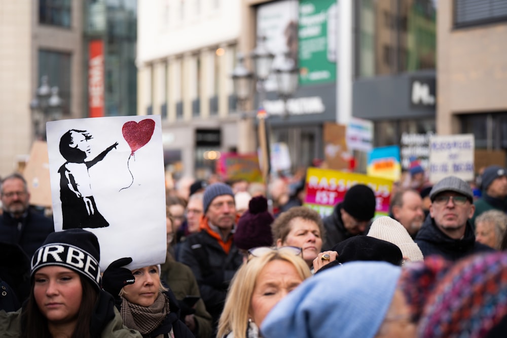 a crowd of people standing around each other holding signs