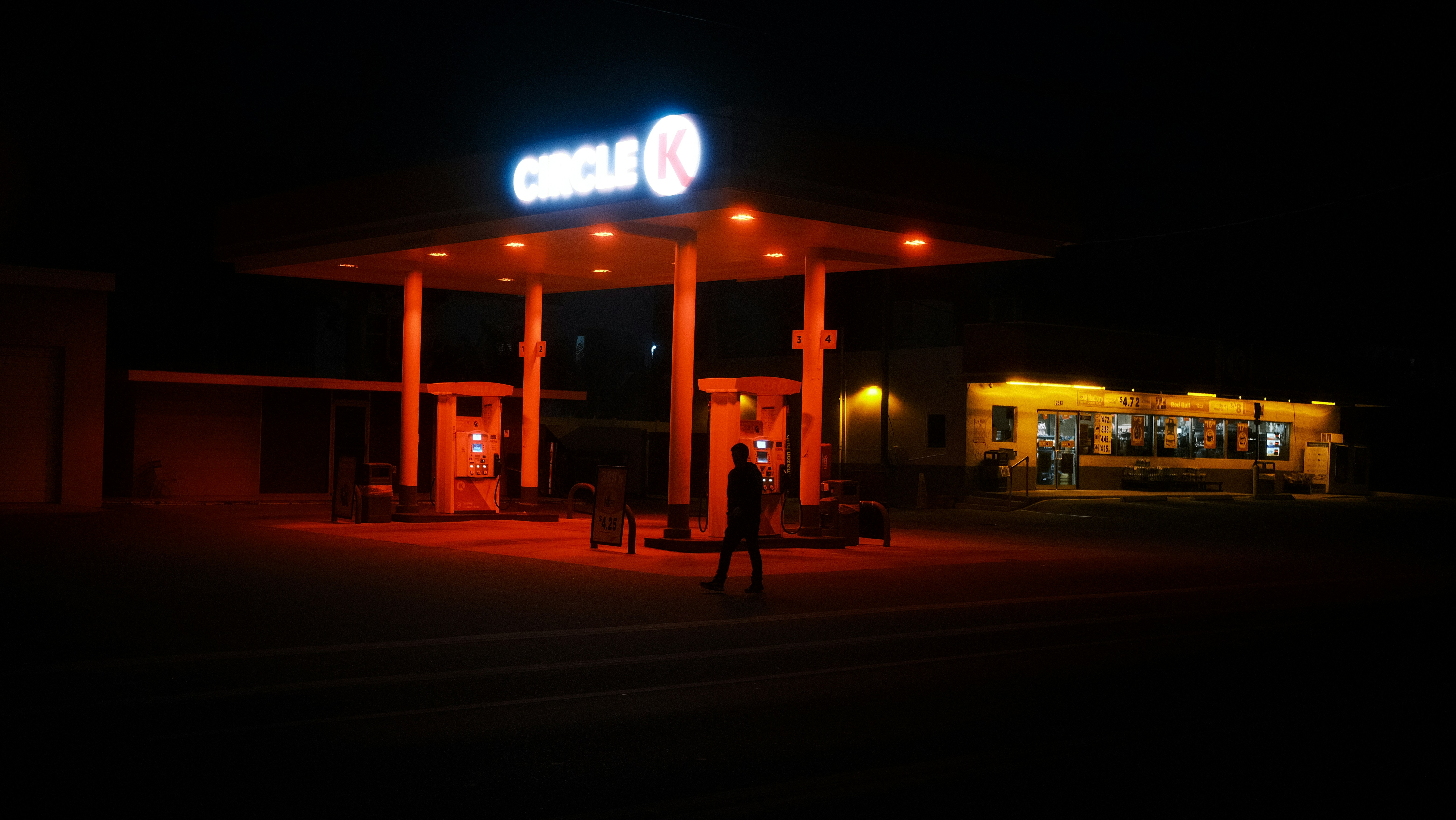 a gas station lit up at night with a neon sign