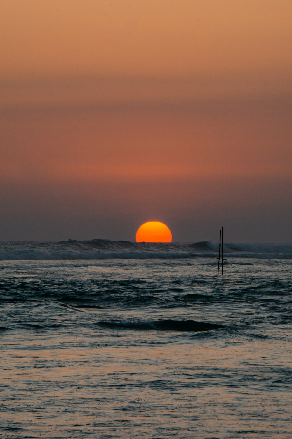 the sun is setting over the ocean with waves