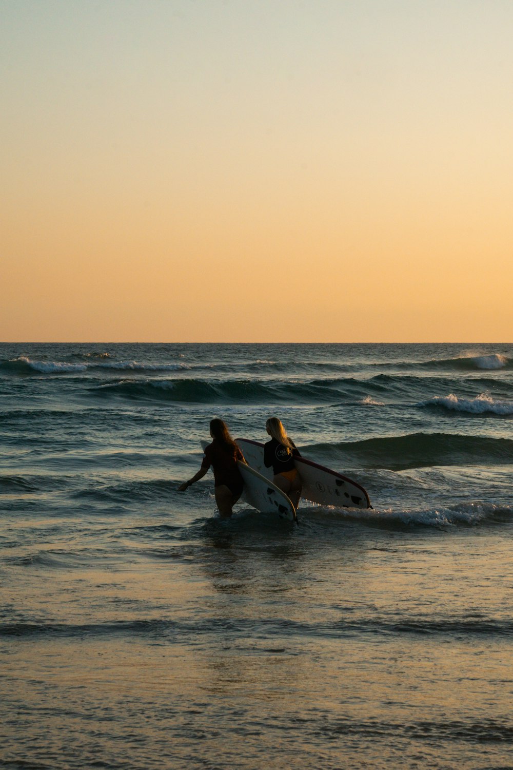 un couple de personnes qui sont dans l’eau avec des planches de surf