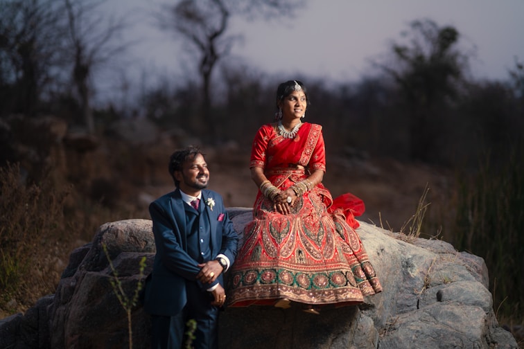 a woman in a red dress and a man in a blue suit sitting on a