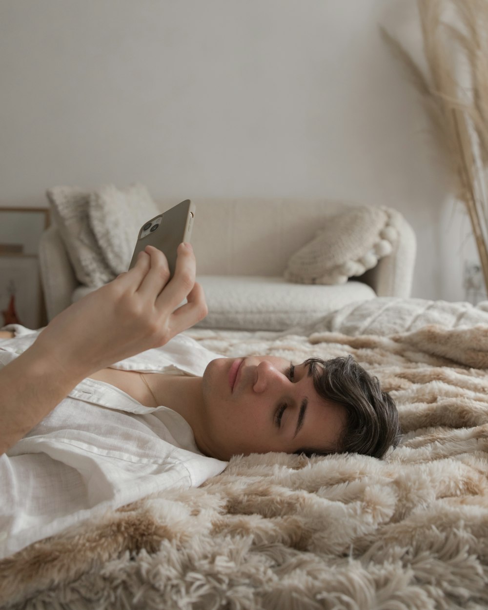 una persona acostada en una cama mirando un teléfono celular