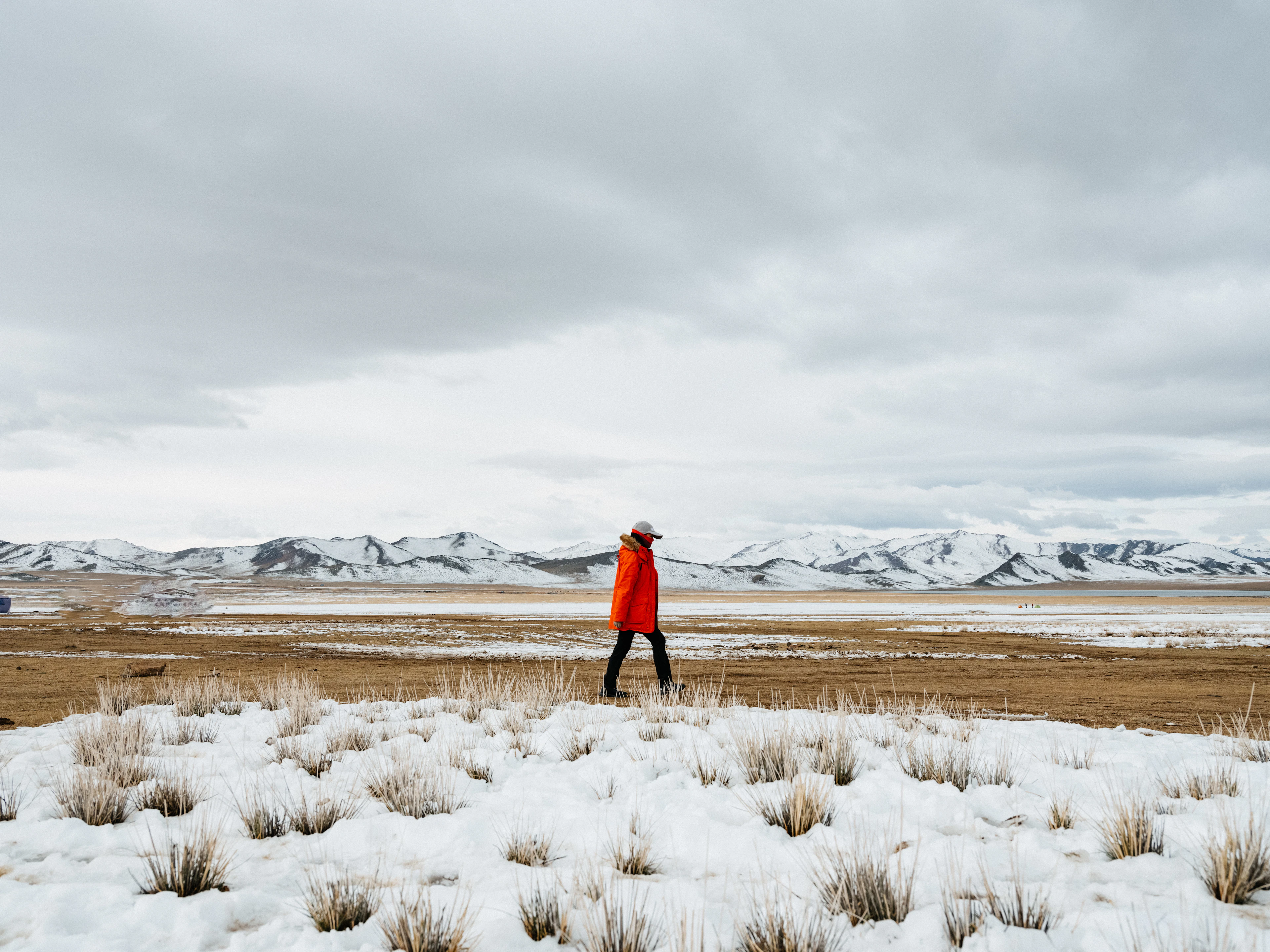 A figure in red walking across snowy steppe