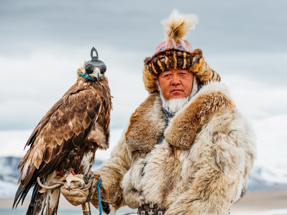 un homme vêtu d’un manteau de fourrure tenant un oiseau de proie