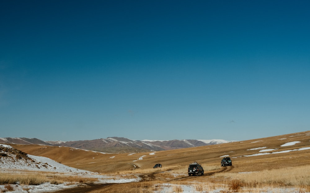 a group of cars driving down a snow covered road