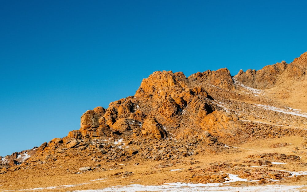 a rocky mountain with snow on the ground