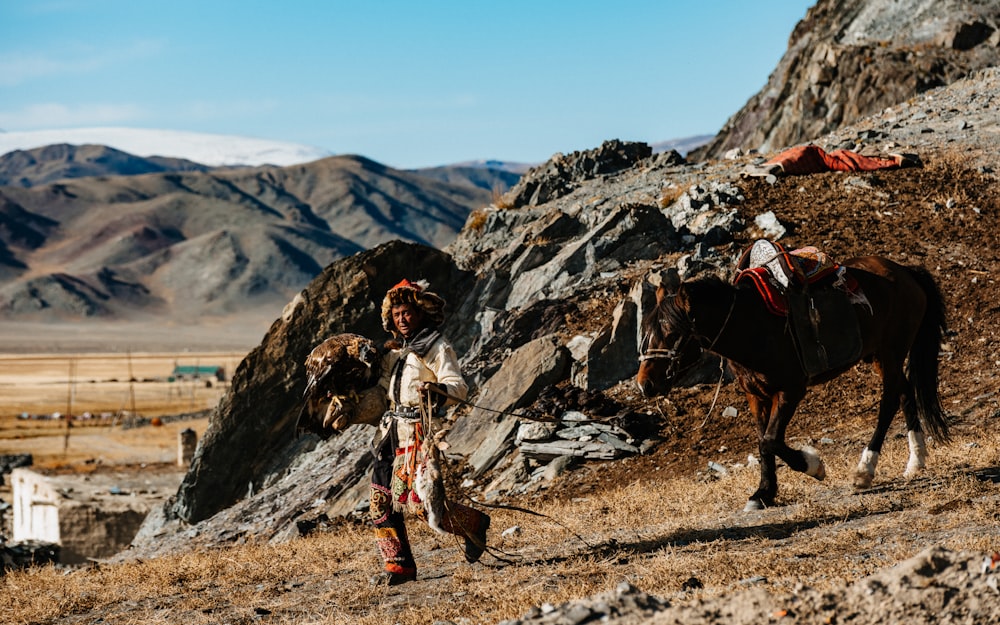 a man walking a horse down a dirt road