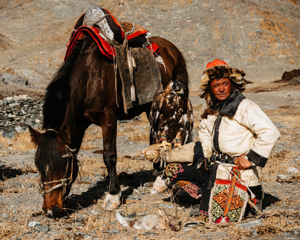 a man sitting next to a brown horse