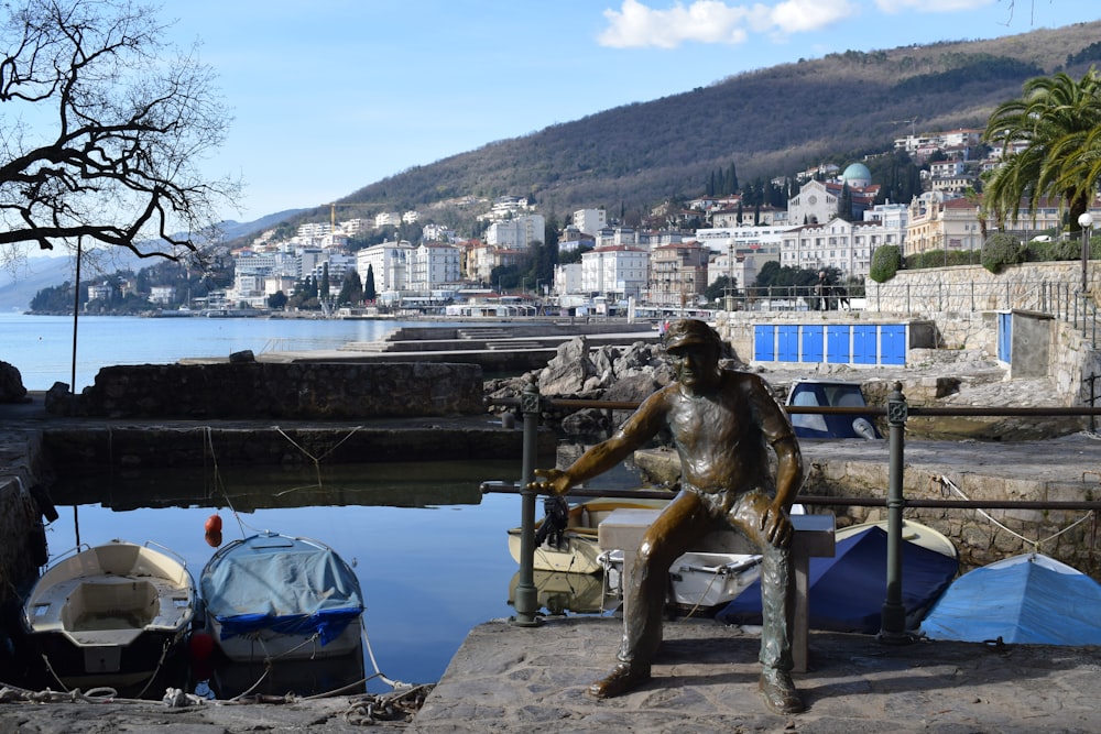 a statue of a man sitting next to a body of water