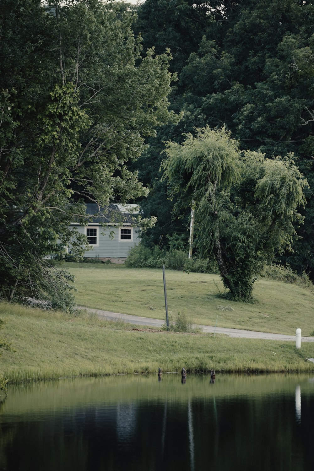 a house sitting on top of a lush green field next to a lake