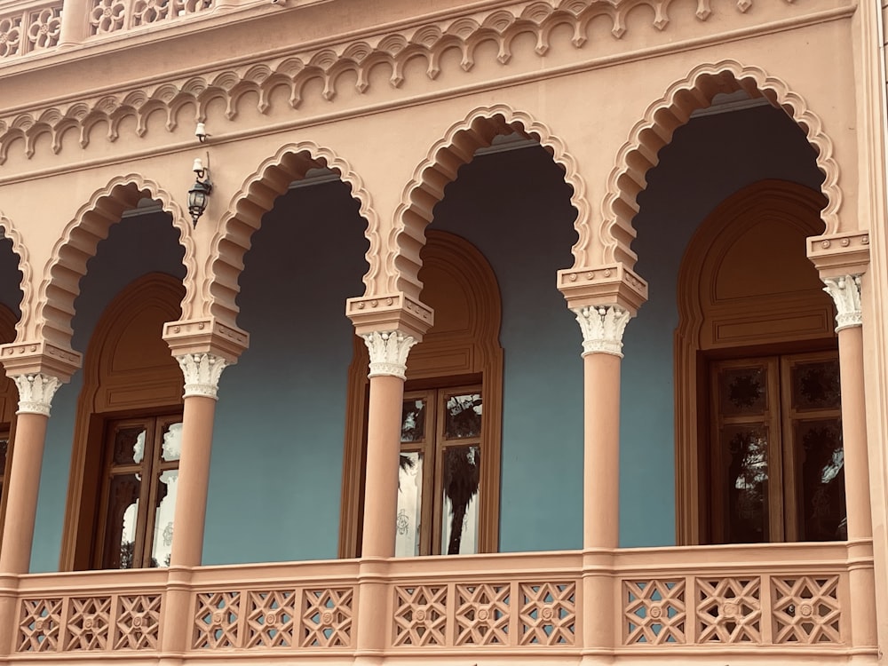 a pink building with arches and columns on the front of it