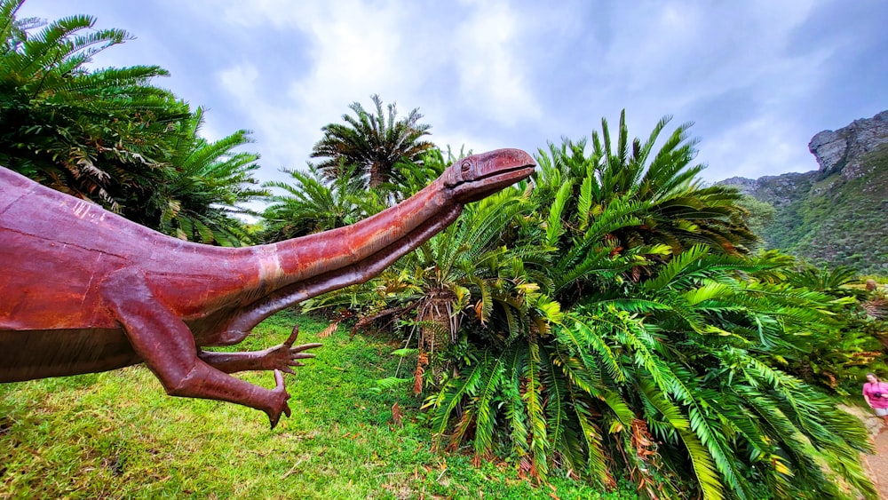 a large dinosaur statue in a lush green field
