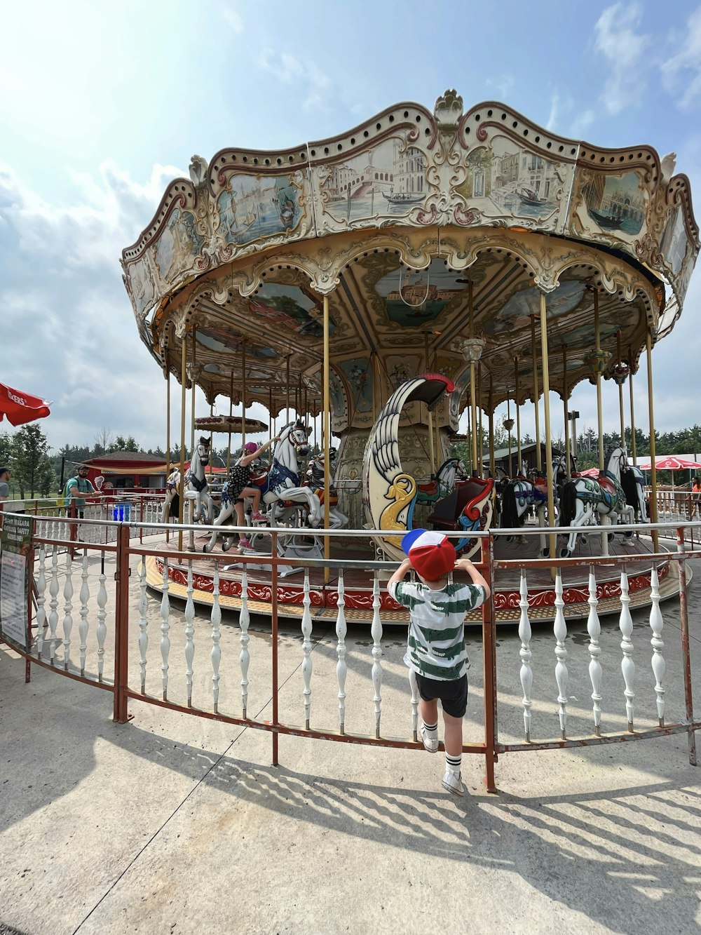 a little boy standing in front of a merry go round