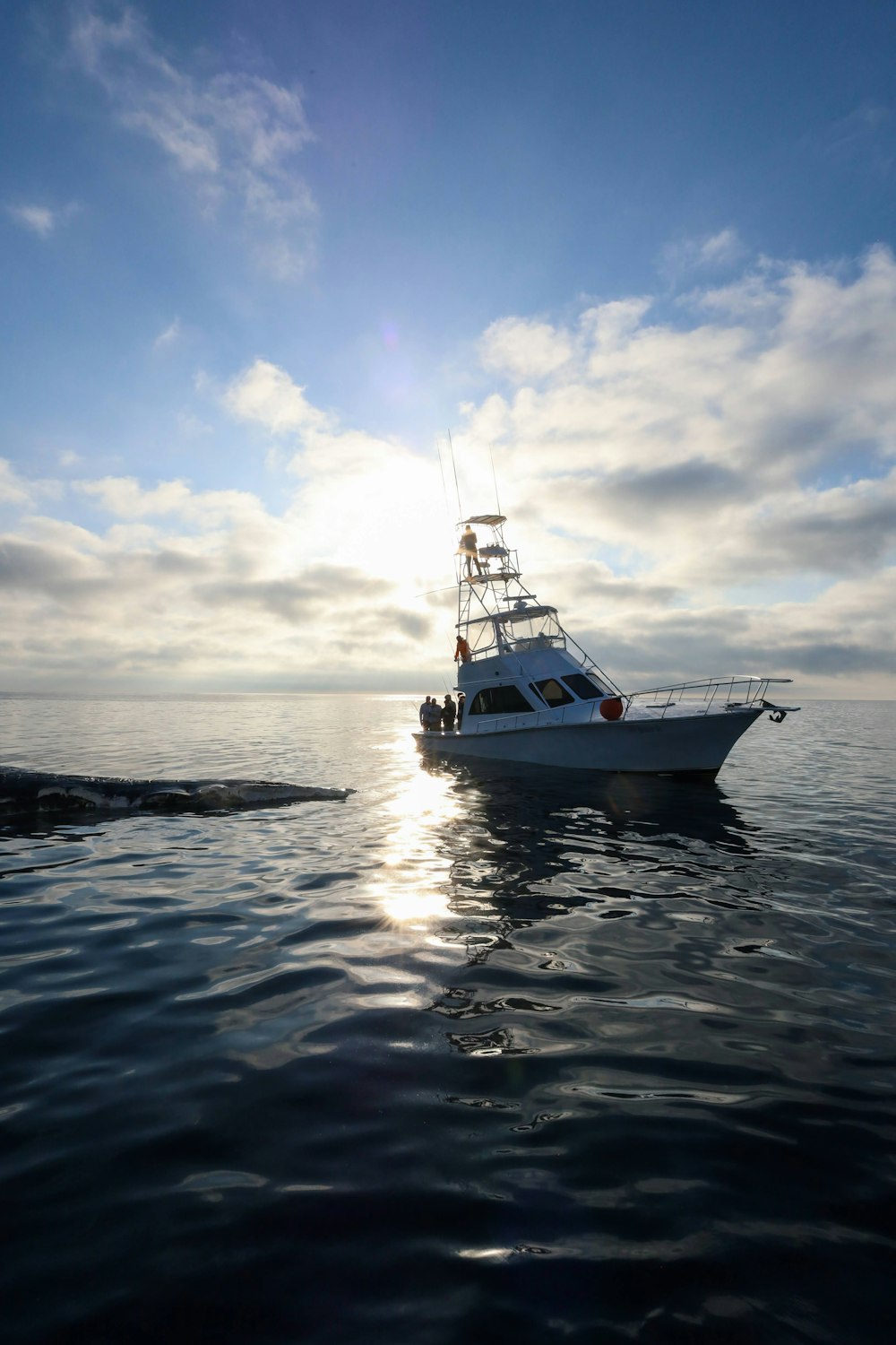 Un barco en el agua con el sol brillando a través de las nubes