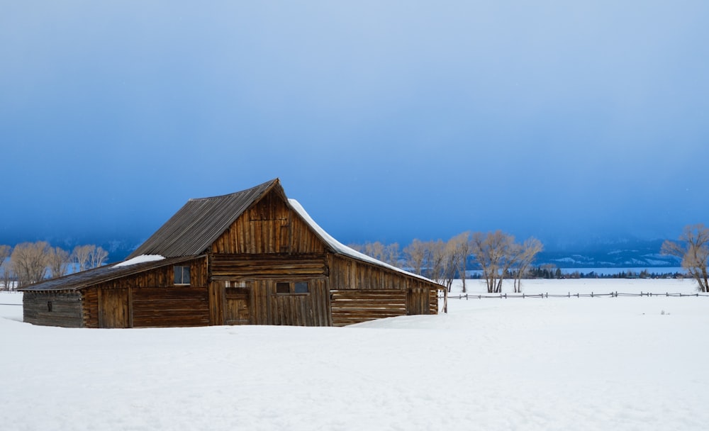 a barn in the middle of a snowy field