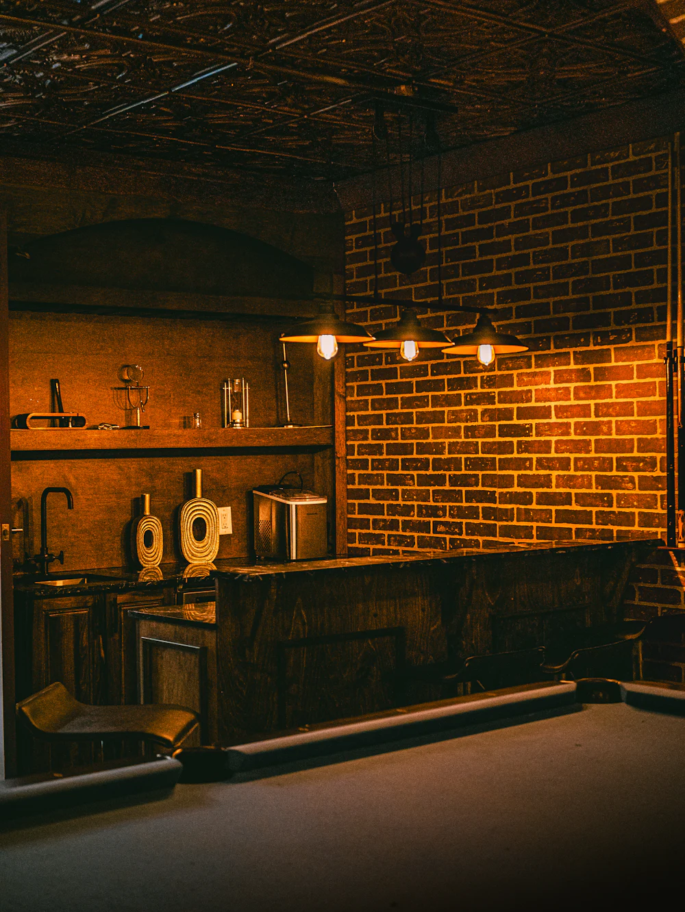 A warm brick room with pendant bulbs over a bar and dark wood.