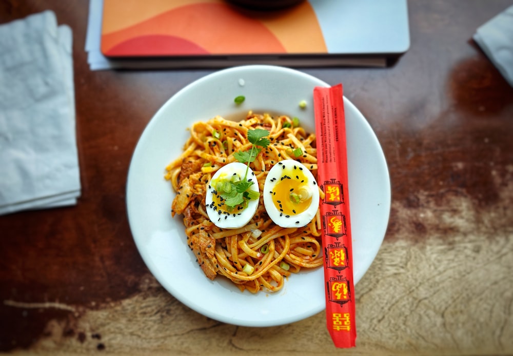a white plate topped with noodles and hard boiled eggs