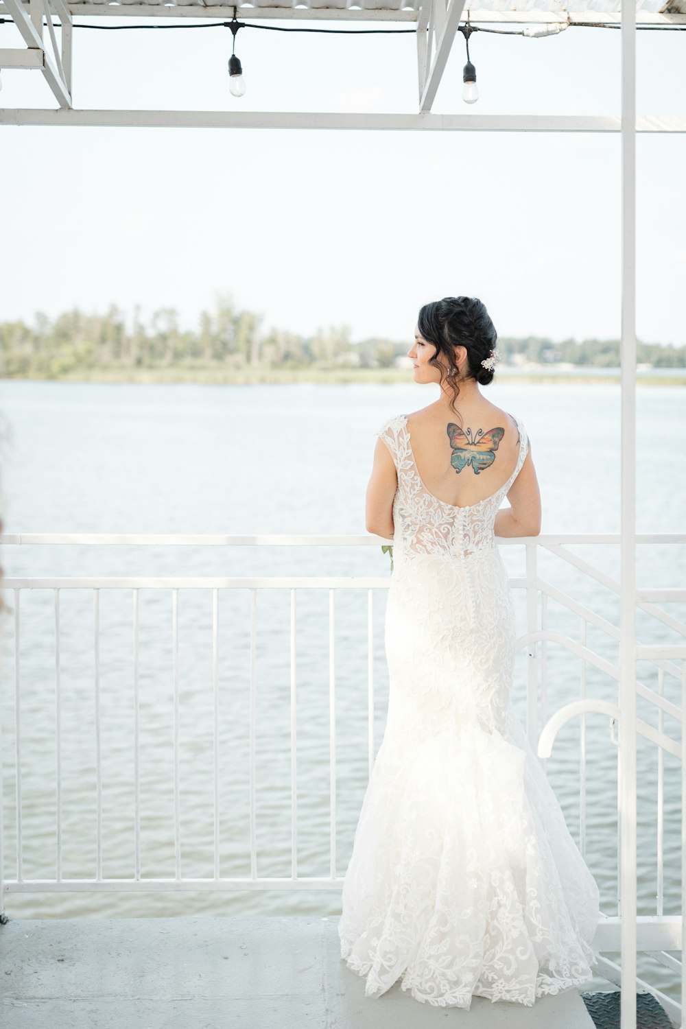 a woman in a wedding dress looking out over the water