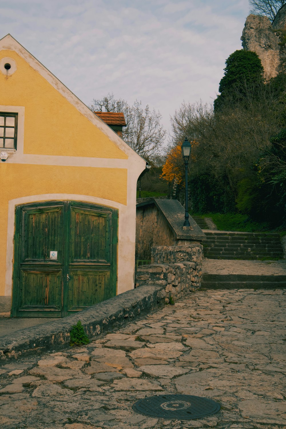 a yellow house with a green door on a cobblestone street