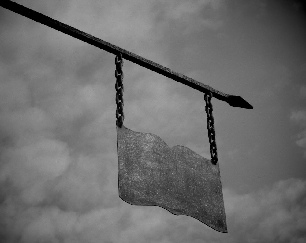 a black and white photo of a sign hanging from a chain