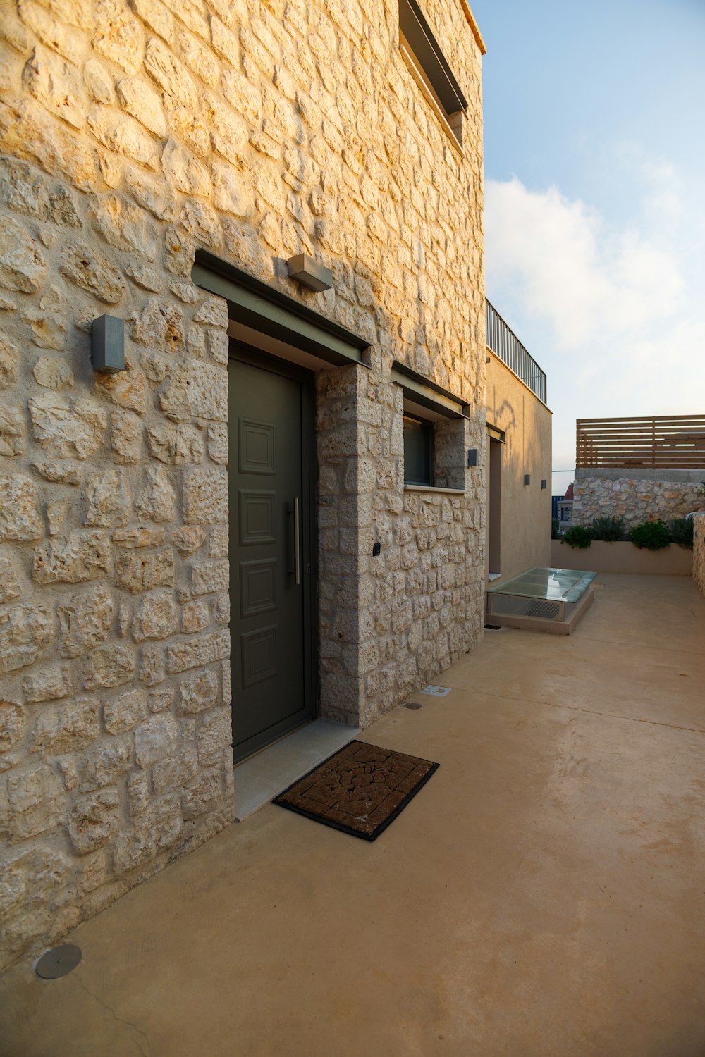 a stone building with a door and a brown door mat