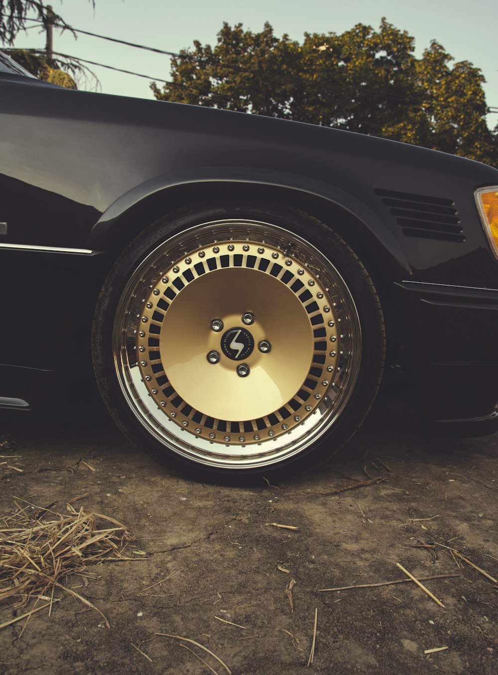 a black car with gold rims parked on the side of the road