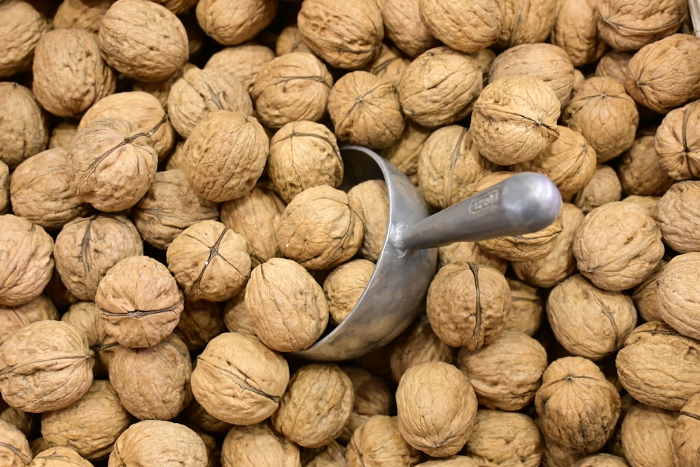 a scoop of walnuts sitting on top of a pile of nuts